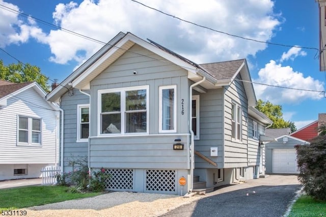 bungalow featuring a garage and an outbuilding