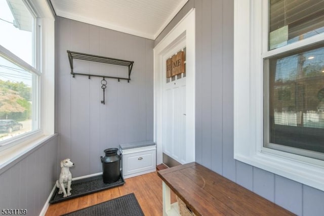 mudroom with crown molding, light hardwood / wood-style flooring, and wood walls