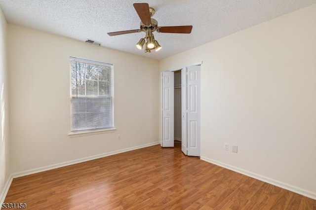 unfurnished bedroom with a textured ceiling, hardwood / wood-style flooring, and ceiling fan