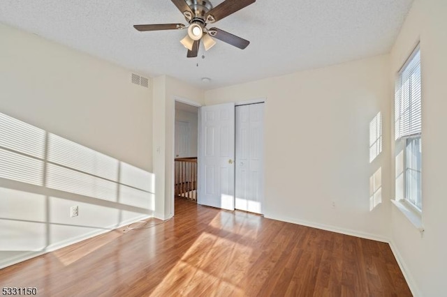 empty room featuring ceiling fan, wood-type flooring, and a textured ceiling