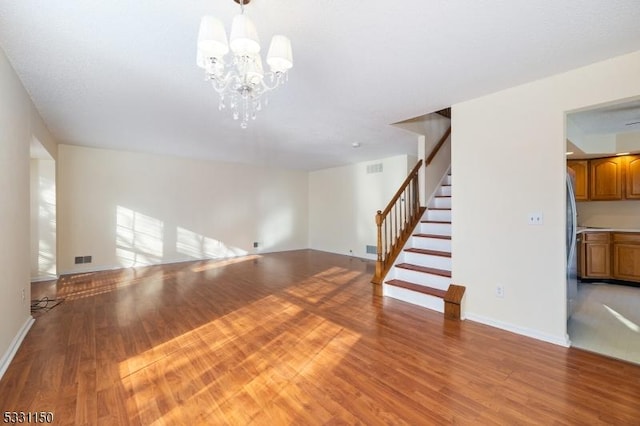 unfurnished living room featuring light wood-type flooring and an inviting chandelier