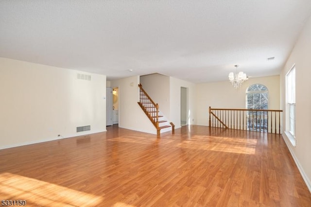 spare room featuring a chandelier and hardwood / wood-style flooring