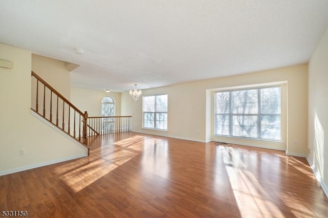 unfurnished living room with hardwood / wood-style floors and an inviting chandelier