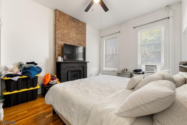 bedroom with ceiling fan, cooling unit, and hardwood / wood-style flooring