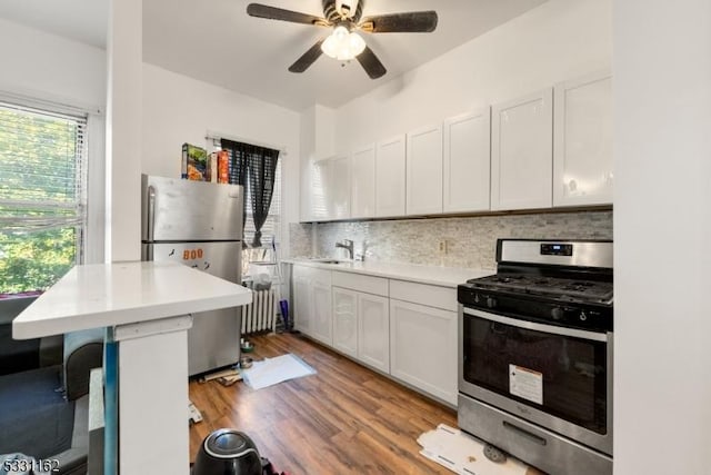 kitchen with white cabinets, appliances with stainless steel finishes, light hardwood / wood-style floors, and decorative backsplash