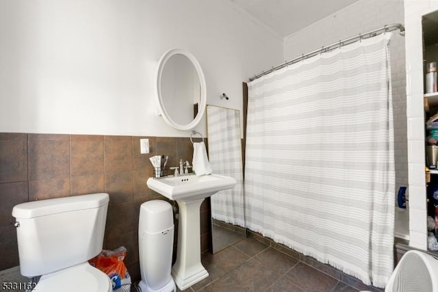 bathroom with curtained shower, tile patterned flooring, tile walls, and toilet