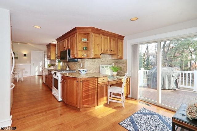 kitchen featuring light stone counters, light wood-style floors, decorative backsplash, and white gas range