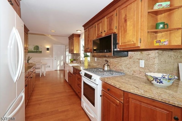 kitchen with stainless steel appliances, brown cabinets, and light stone counters