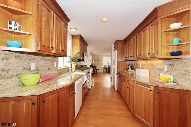 kitchen featuring white appliances, light wood-style floors, light stone countertops, open shelves, and brown cabinetry