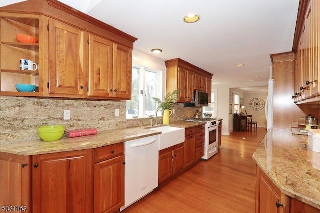 kitchen with white appliances, tasteful backsplash, light wood-style flooring, light stone counters, and a sink