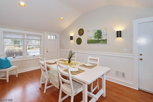 dining space featuring lofted ceiling, wainscoting, visible vents, and wood finished floors