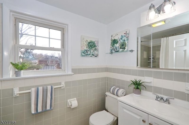 full bath with a shower with curtain, vanity, toilet, and tile walls