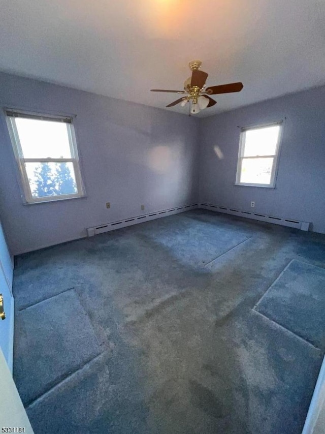 carpeted spare room with ceiling fan and a baseboard radiator