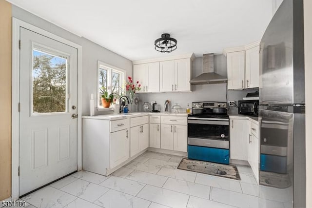 kitchen featuring white cabinets, stainless steel appliances, and wall chimney exhaust hood