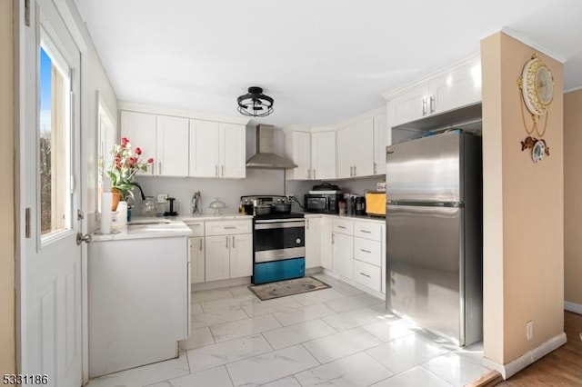 kitchen with sink, white cabinets, stainless steel appliances, and wall chimney range hood