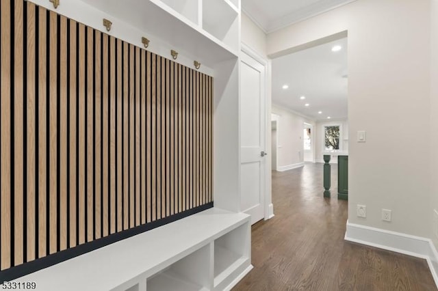 mudroom featuring dark wood-style flooring, crown molding, and baseboards