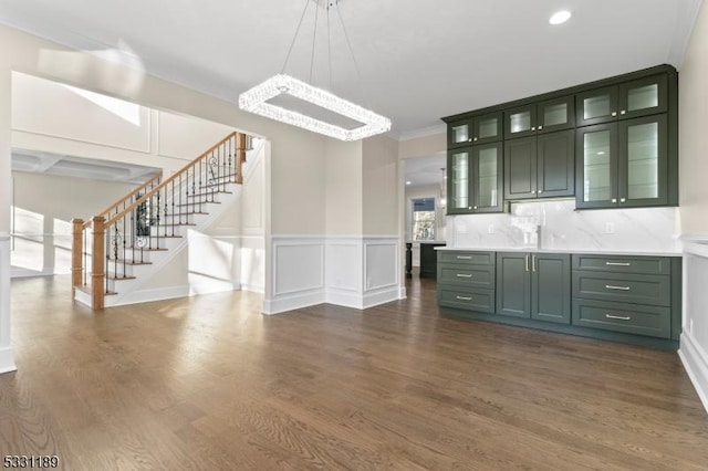 bar featuring a decorative wall, dark wood-style flooring, ornamental molding, stairway, and pendant lighting