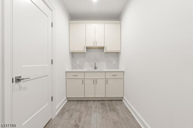 interior space with light wood-type flooring, a sink, and baseboards