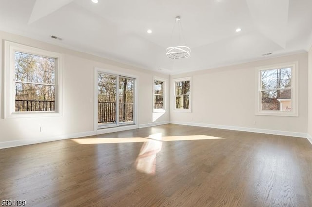 spare room with a tray ceiling, recessed lighting, wood finished floors, and baseboards