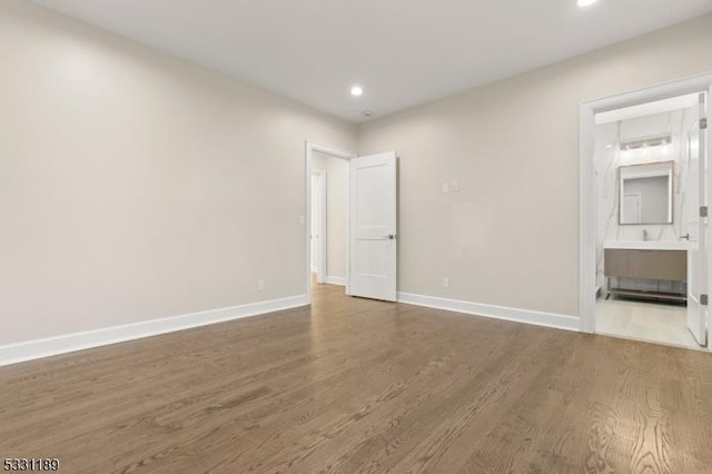 unfurnished bedroom featuring connected bathroom, baseboards, wood finished floors, and recessed lighting