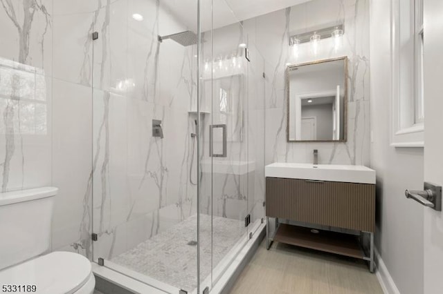 bathroom featuring tile walls, a marble finish shower, vanity, and toilet