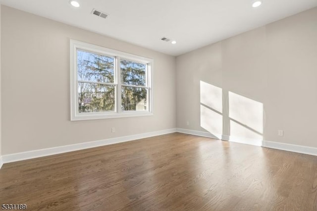 spare room with baseboards, wood finished floors, and recessed lighting