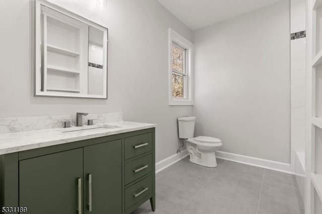 bathroom with tile patterned floors, toilet, vanity, baseboards, and walk in shower