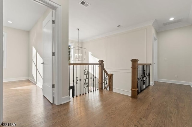 hallway with wood finished floors, an upstairs landing, and visible vents