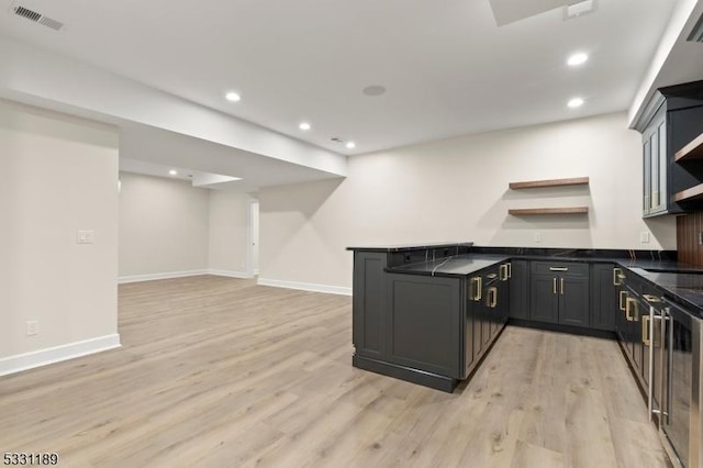 kitchen with a peninsula, visible vents, open shelves, light wood finished floors, and dark countertops