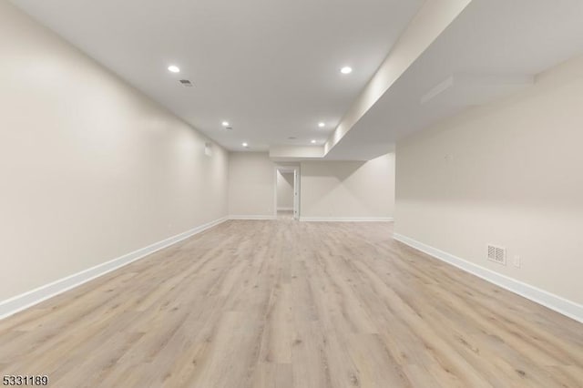 finished basement with light wood-style floors, recessed lighting, visible vents, and baseboards