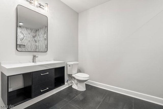 bathroom with toilet, vanity, baseboards, and tile patterned floors