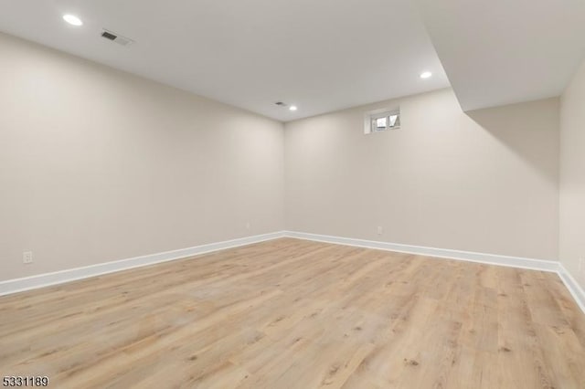 below grade area with light wood finished floors, recessed lighting, visible vents, and baseboards