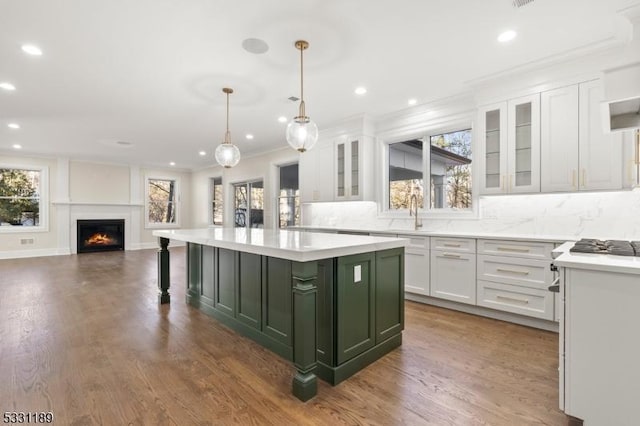 kitchen featuring decorative backsplash, a kitchen island, light countertops, white cabinetry, and green cabinetry