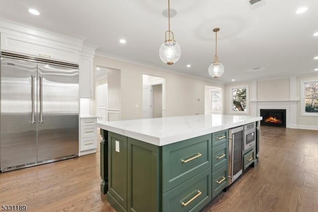 kitchen featuring light countertops, white cabinetry, wood finished floors, green cabinetry, and built in appliances