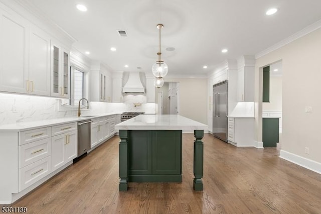 kitchen with a center island, crown molding, custom exhaust hood, appliances with stainless steel finishes, and white cabinets