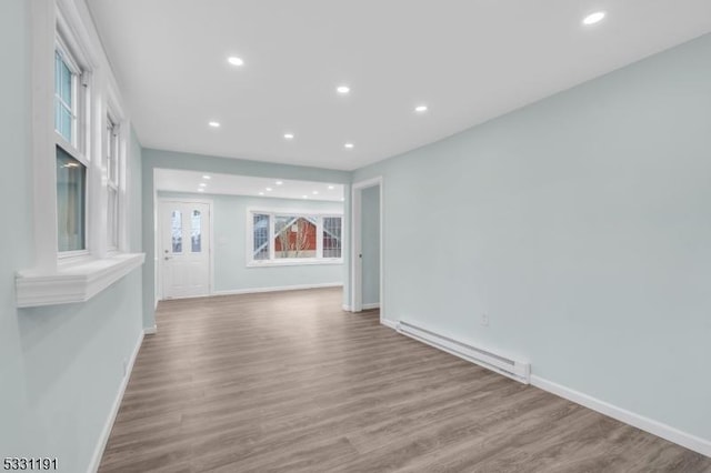 spare room featuring a baseboard heating unit and light hardwood / wood-style flooring