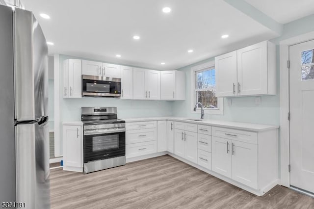 kitchen featuring stainless steel appliances, white cabinets, and sink