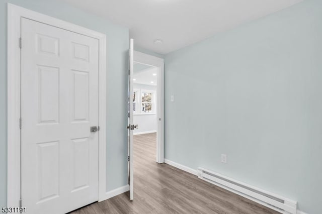 spare room with a baseboard heating unit and light hardwood / wood-style floors