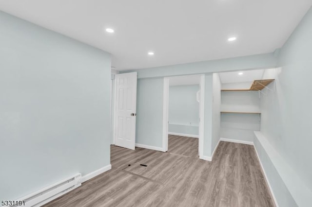 interior space featuring baseboard heating and light hardwood / wood-style flooring