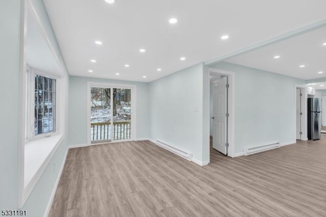 empty room with a baseboard heating unit and light hardwood / wood-style floors