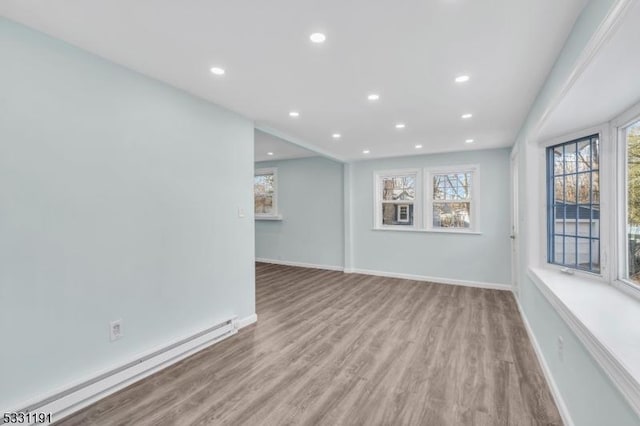 spare room with a baseboard heating unit and light wood-type flooring