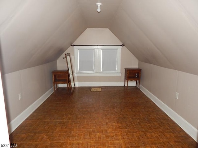 additional living space with dark parquet floors and lofted ceiling