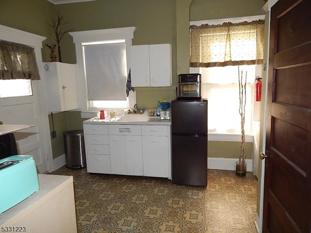 kitchen featuring white cabinetry and fridge