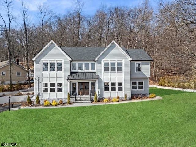 rear view of property with a standing seam roof, roof with shingles, metal roof, and a yard