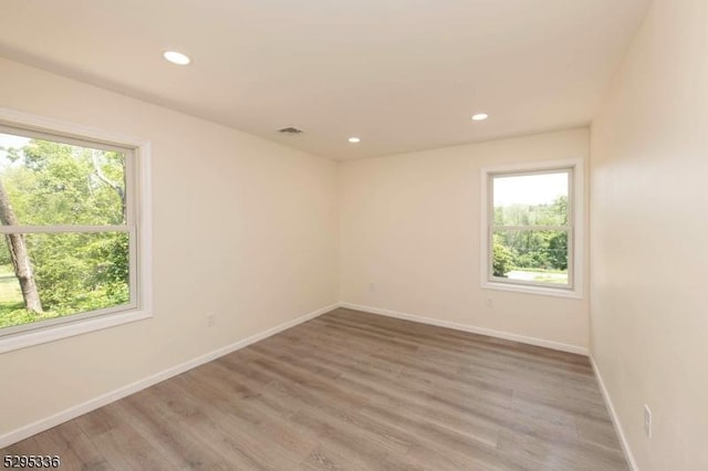 empty room with hardwood / wood-style flooring and a wealth of natural light