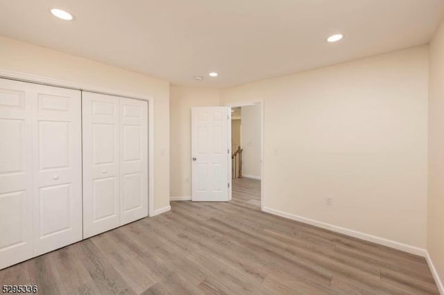 unfurnished bedroom with light wood-type flooring and a closet