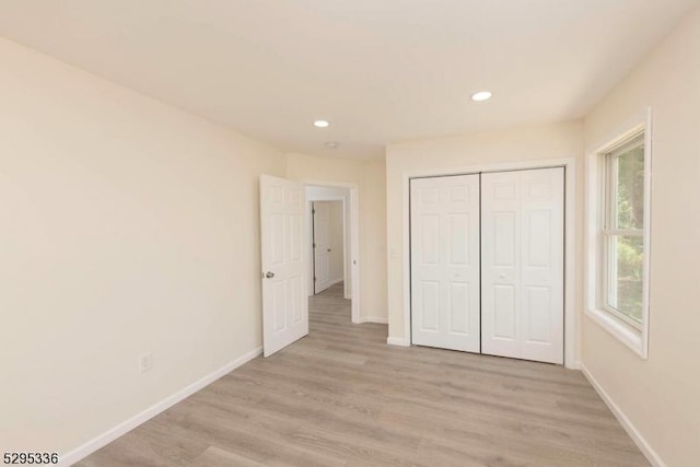 unfurnished bedroom with a closet and light hardwood / wood-style floors