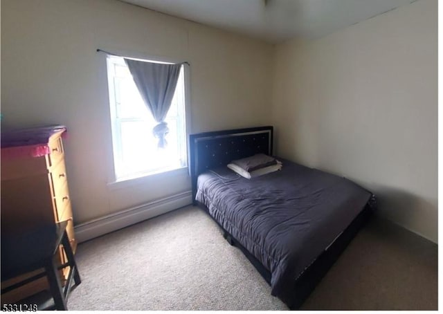 carpeted bedroom featuring a baseboard heating unit