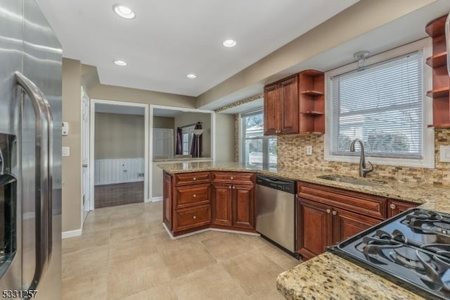 kitchen with a healthy amount of sunlight, light stone counters, sink, and stainless steel appliances