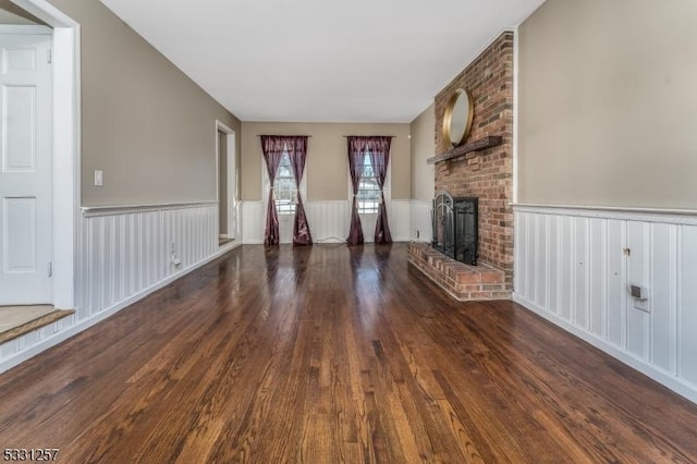 unfurnished living room with dark wood-type flooring and a brick fireplace